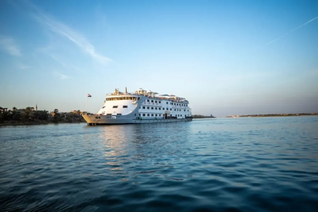 Traditional 5-star Nile cruise ship sailing past lush riverbanks at golden hour